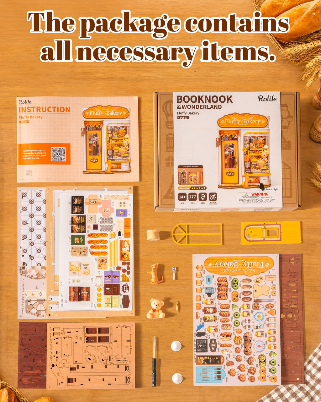 A DIY craft kit for building a 'Fruity Bakery' set from the brand Rolife, displayed on a wooden tabletop with its instruction manual, assembly box, stickers, wooden pieces, and tools. The image includes a text overlay at the top stating 'The package contains all necessary items.