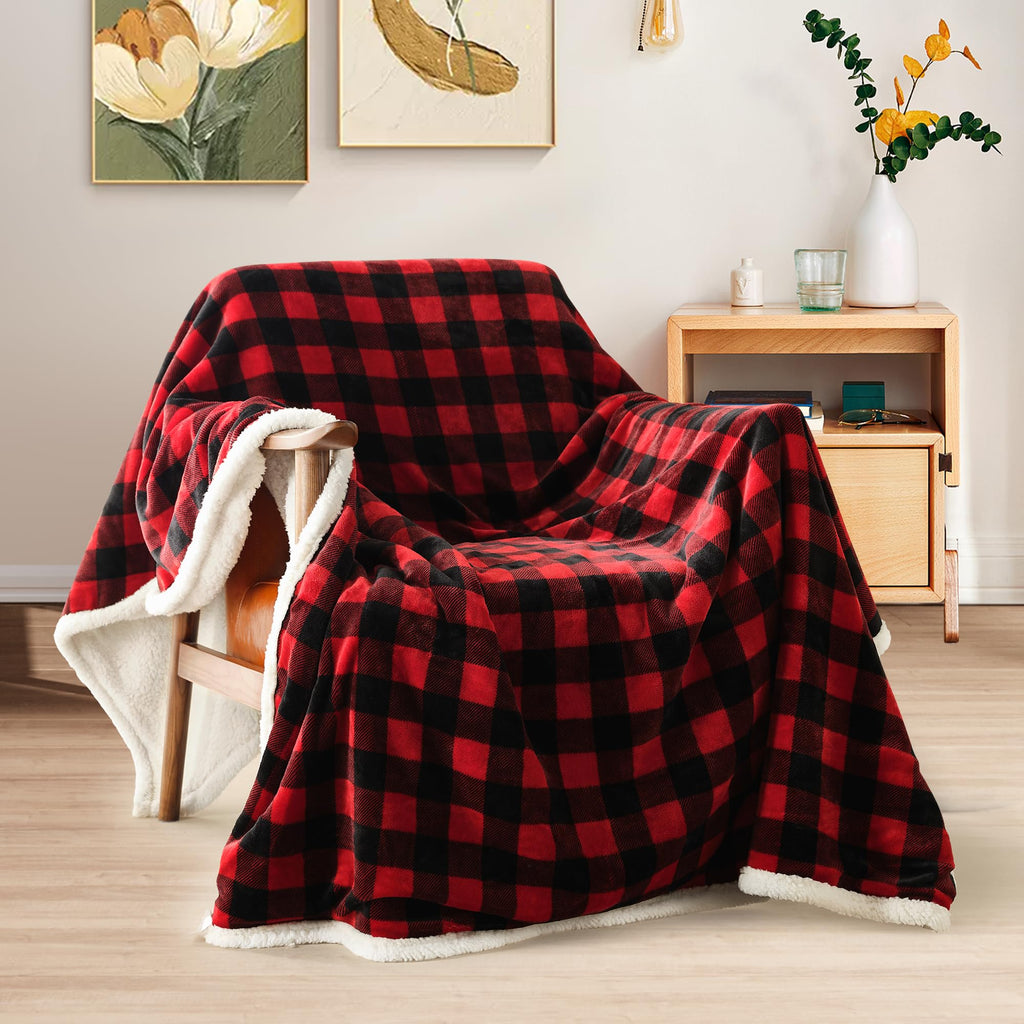 Red and black buffalo plaid sherpa throw blanket draped over a wood armchair showing white fleece lining in a modern living room with floral wall art