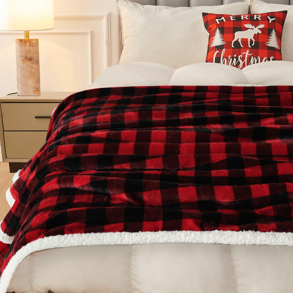 Red and black checkered blanket on a bed with a Christmas pillow.