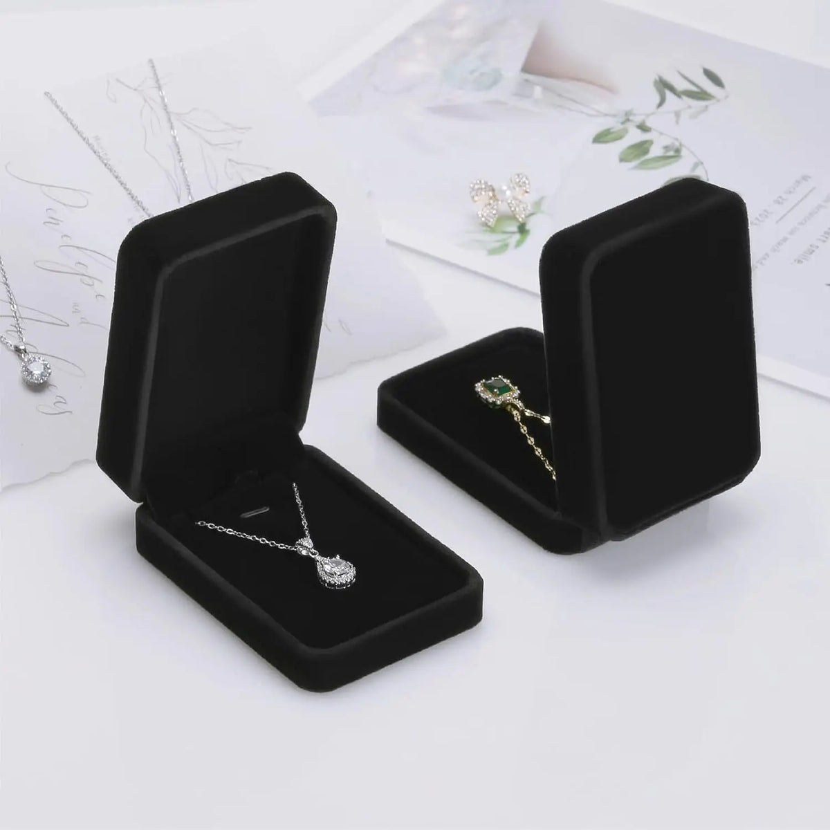 Black jewelry display cases with necklaces on a white surface