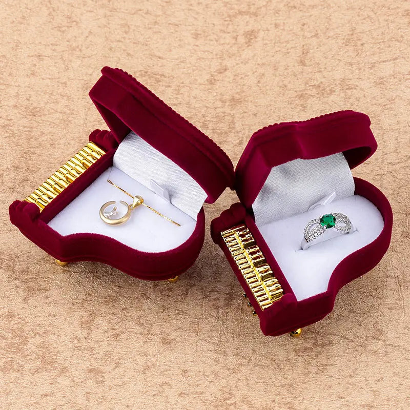 Two open red velvet jewelry boxes with gold and silver jewelry on a beige background