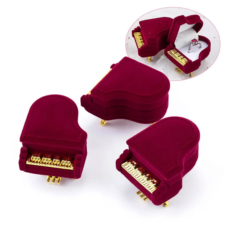 Red piano-shaped jewelry box with gold accents on a white background