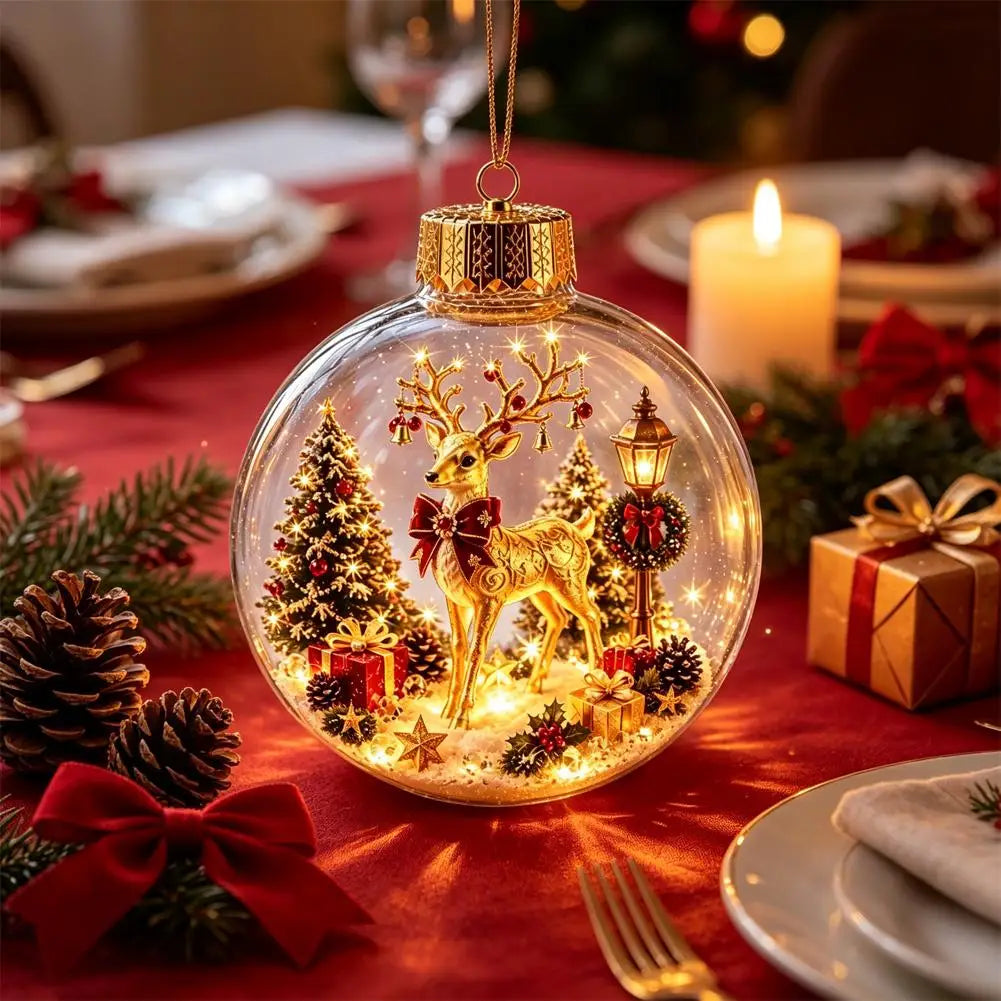 A clear round Christmas ornament hanging on a red tablecloth, featuring a gold reindeer, lit trees, ornaments, and a warm glowing interior. The scene is decorated with pine branches, a candle, wrapped gift boxes, and plates in the background.