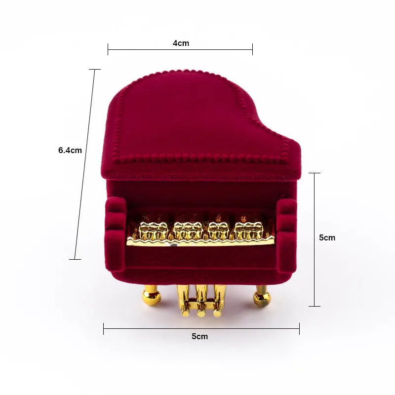 Red velvet toy piano with gold accents and measurements on a white background
